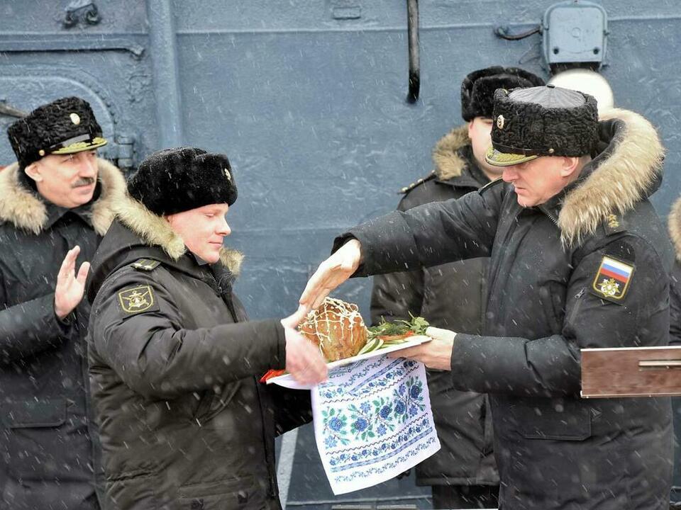 Командиру корабля Андрею Жаркову традиционного поросенка вручает командующий СФ Николай Евменов.