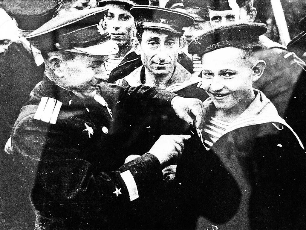 Командир бригады торпедных катеров СФ А. В. Кузьмин вручает юнге Саше Ковалеву орден Красной Звезды.